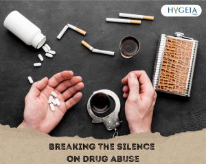 A man's hands on a table scattered with pills, pills container, cigarettes, pocket flask, having pills in one and handcuff on other hand with text saying "breaking the silence on drug abuse" from frrepik.com